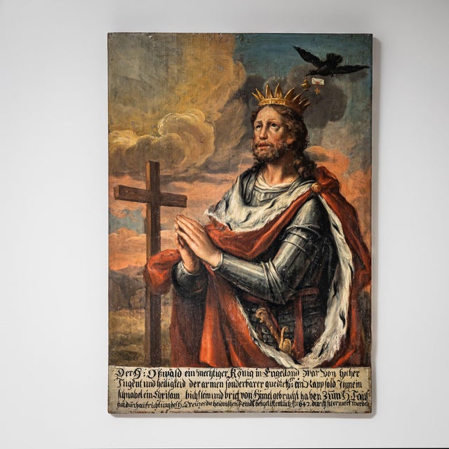 Depiction of Saint Oswald of England wearing armor and a red ermine mantle, crowned as king. In the background a raven...