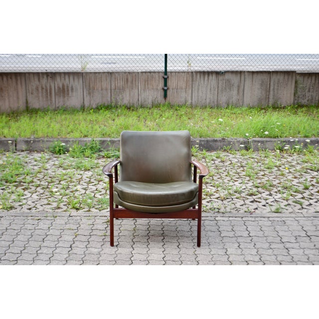 Lounge chair in rare olive leather and teak, designed by Ib Kofod-Larsen, 1970s. A striking example of Scandinavian modern...