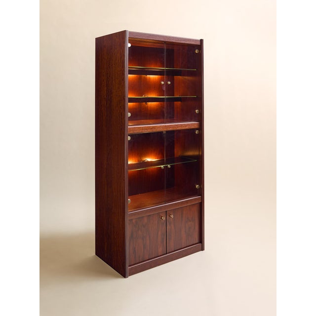 A beautifully crafted rosewood curio cabinet with rich, expressive grain and warm interior lighting. Glass shelving and...