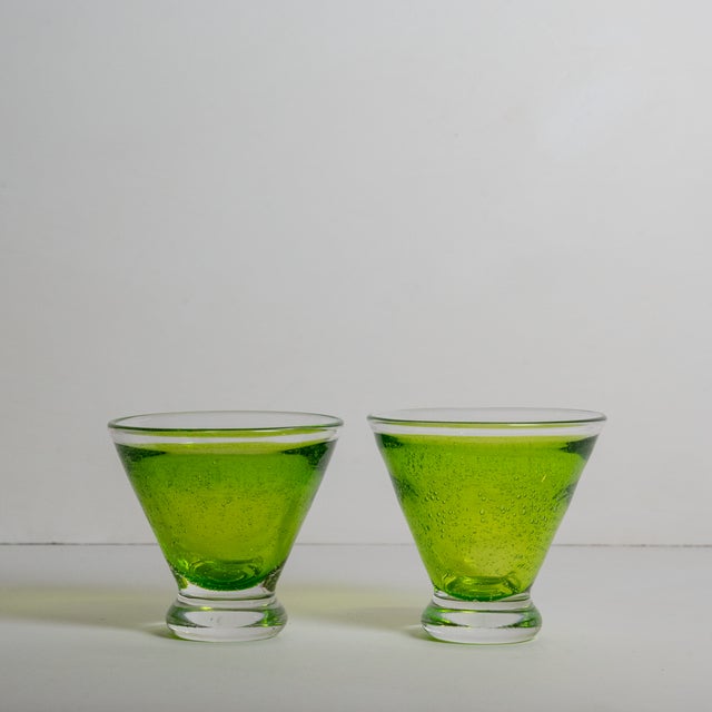A lively pair of hand-blown cocktail glasses featuring a vibrant lime green hue and tiny bubbles throughout the glass....