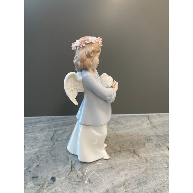 Handcrafted in Spain, this porcelain figurine depicts a beautifully serene young angel tenderly cradling a small rabbit....
