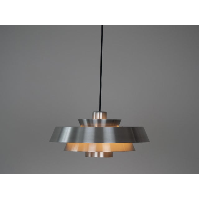The aluminum Nova lamp, designed by Jo Hammerborg in 1963. When lit, the lamp provides a soft, glare-free downward glow,...