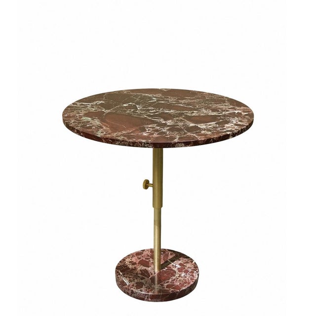 Adjustable height round table in red Levanto marble. It has a refined, elegant design, thanks to the material used to make...