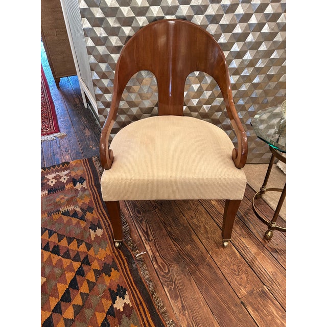 Sensually shaped spoonback walnut chairs having curved back and stylish splayed legs that terminate in brass casters....