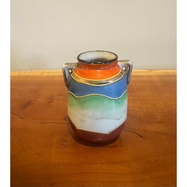 Marked Made in Japan. A vibrant miniature vase adorned with a richly colored, hand-painted figure framed by ornate...