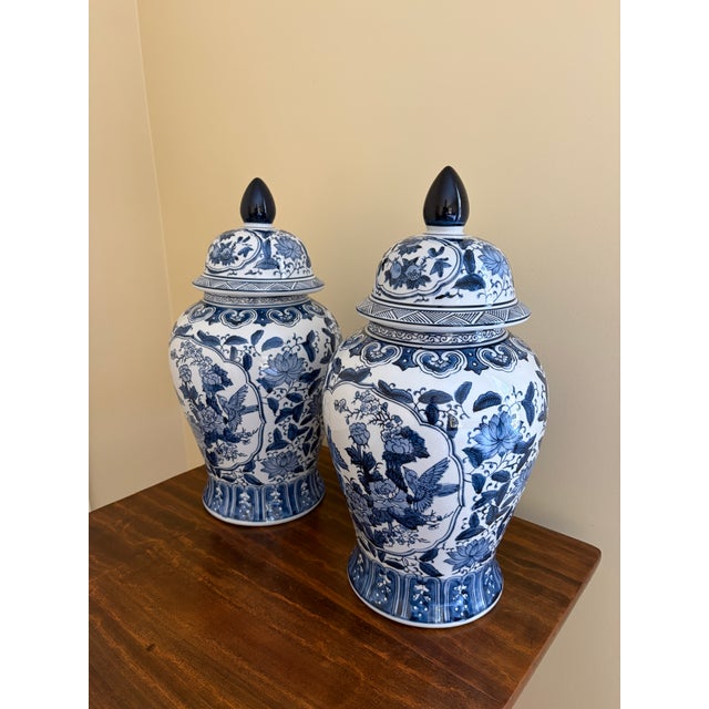 A beautiful pair of large Chinoiserie blue and white porcelain covered ginger jars or temple jars featuring birds and a...