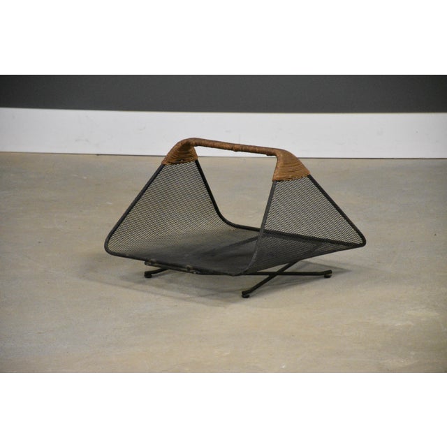 A mid century modern iron mesh with rush wrapped handle magazine rack or log holder designed by Tony Paul. Minor oxidation...