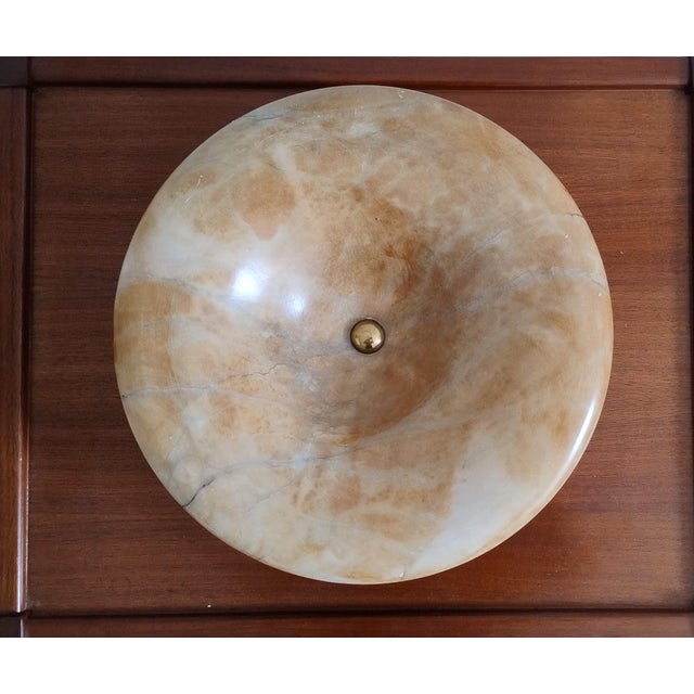 Elegant French decorative bowl made from warm-toned natural alabaster and resting on a solid, gilt bronze base marked...