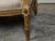 A French Louis XVI style giltwood wingback settee from the 19th century, with carved foliage motifs and distressed patina....