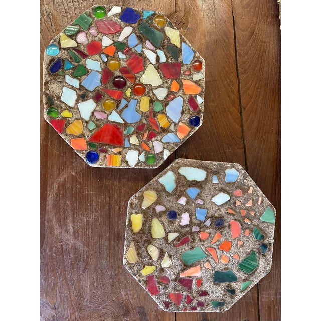 Pair of vintage handmade stepping stones featuring colorful mosaic glass fragments set into solid concrete bases. Each...