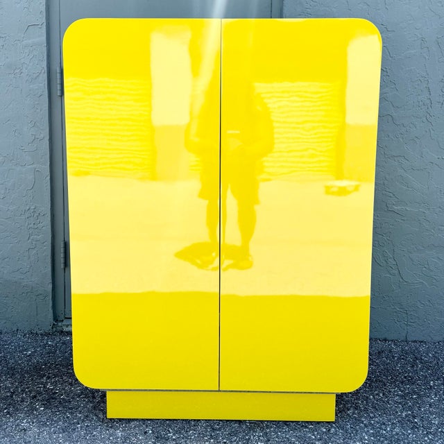 A striking Postmodern waterfall cabinet, finished in radiant high-gloss yellow laminate with bold rounded edges and a...