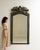 This mirror makes its impression through black frame with ornate gilt bronze crest, foliate motif. Originating in France...