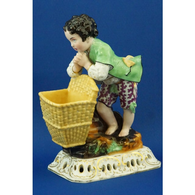 Sculpture, figurine in hard-paste porcelain, polychrome, entirely hand-decorated, depicting a child with a basket, hand-...