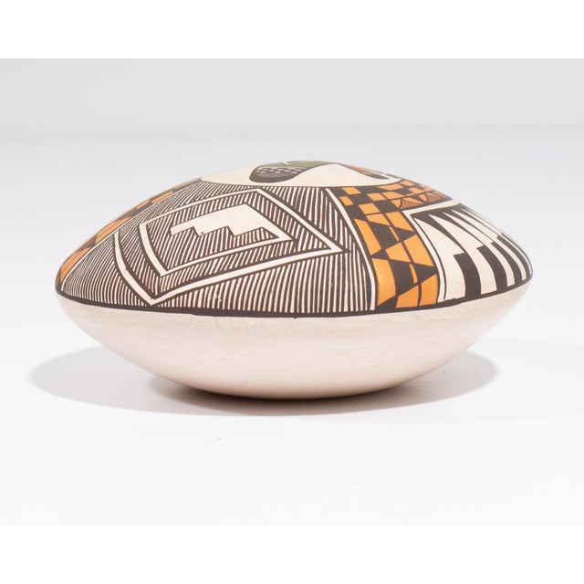 A pottery seed pot by the Acoma potter Diane Lewis. This small seed pot features an intricate design on the top a stylized...
