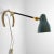 A sculptural 1950s table lamp, also mountable on the wall, crafted from solid brass with a painted metal shade that can be...