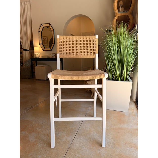 Coastal contemporary counter stool crafted with a crisp white wood frame and natural rattan seat and back for a light,...