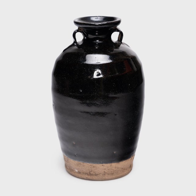 Cloaked inside and out with a glossy black glaze, this antique Chinese pickling pot was originally used for fermenting...
