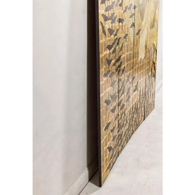 A Hollywood Regency black and gold four-panel screen with hand-painted flying cranes. This Hollywood Regency black and...