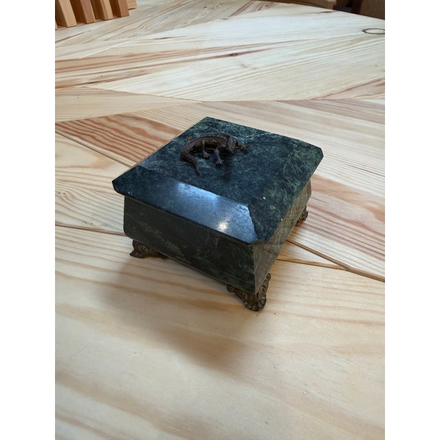 Elegant box is crafted from deep green marble with natural veining, giving it a refined and luxurious appearance. It rests...