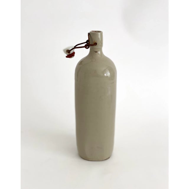 Early 1900s French gray stoneware gin bottle with wired porcelain stopper. Age and patina to this rustic handmade piece.