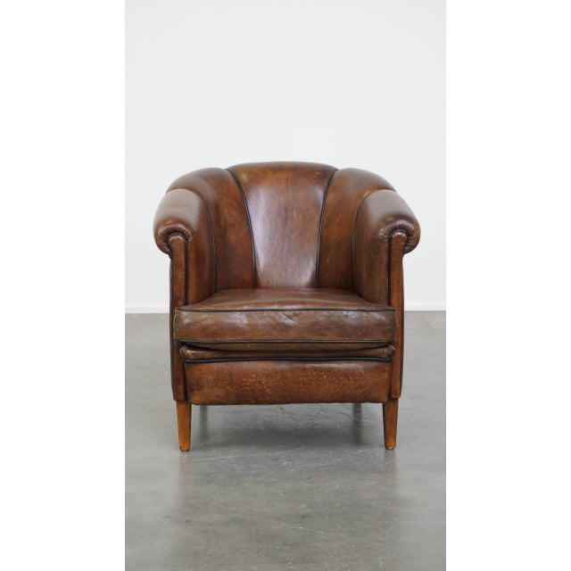 Special, characteristic and stately dark sheep leather club chair with a finish with black piping. This great sheep...