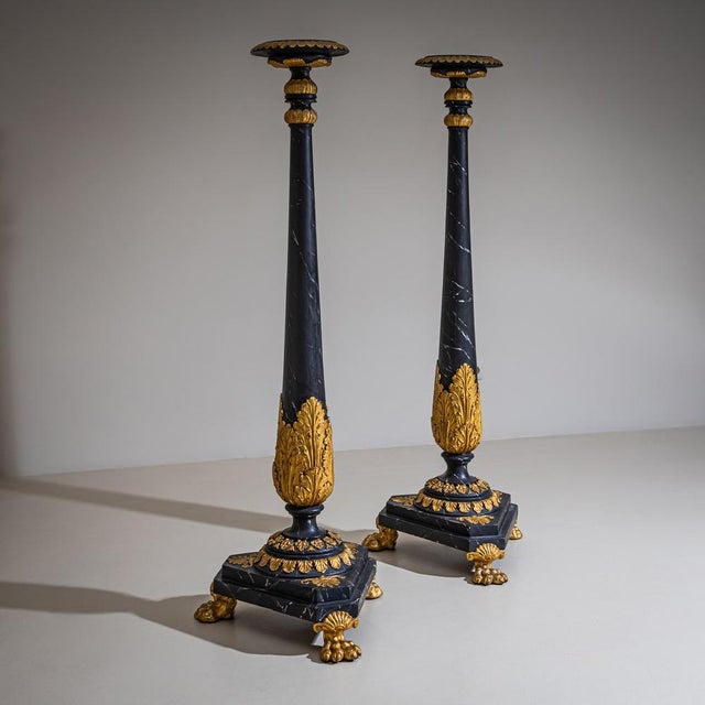 Pair of torcheres on triangular bases with gilded carved paw feet, acanthus leaf decoration and palmettes on the base,...