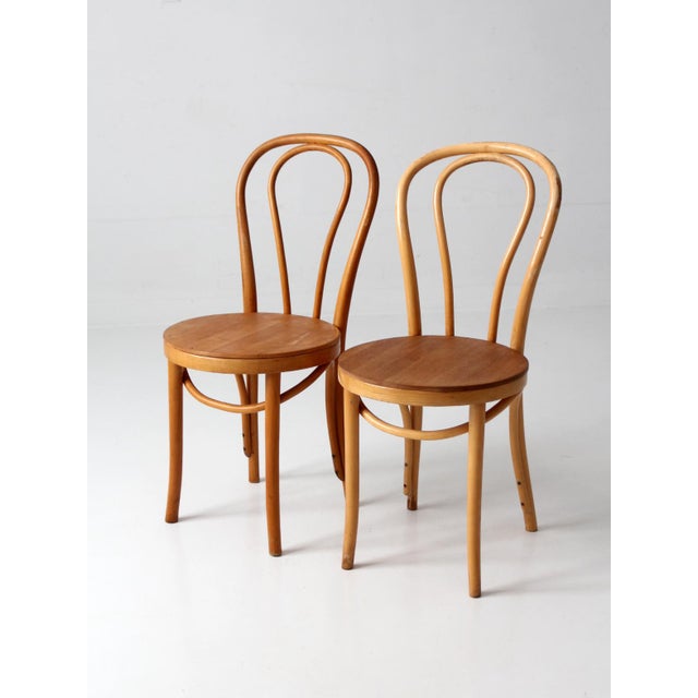 Pair of vintage ZPM Radomsko bentwood café chairs made in Romania, featuring flowing bentwood frames, looping backs, and...