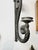 Dramatic vintage wall sconces in heavy cast metal (likely brass), with a long, curving tail that supports a single candle...