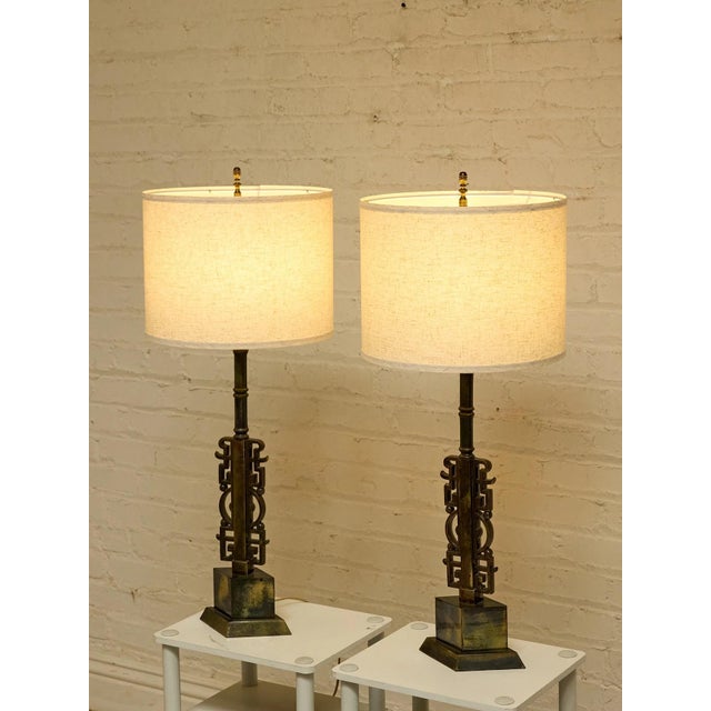 A striking pair of Brutalist-inspired table lamps featuring sculptural steel bases with geometric cutout details and an...