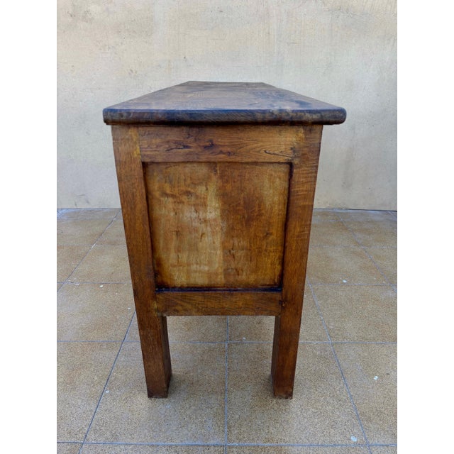 Spanish rustic storage chest in solid chestnut, dating from circa 1880–1920. The front features two carved decorative...