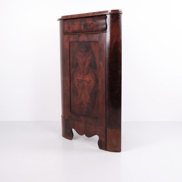 Antique corner cabinet in the Late Empire style, crafted from hand-polished mahogany. The cabinet was made in the 1840s...