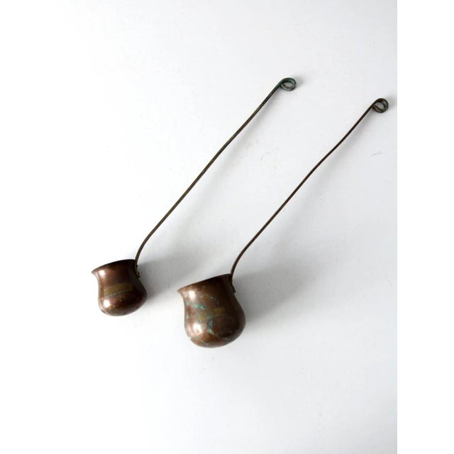Pair of antique copper liquor tasting ladles, including a larger “Rum” ladle and a smaller “Brandy” ladle. Each features a...