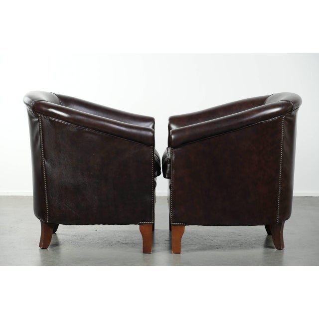 Set of two dark cowhide leather club armchairs in good condition, featuring a timeless and stylish English-style design. :...