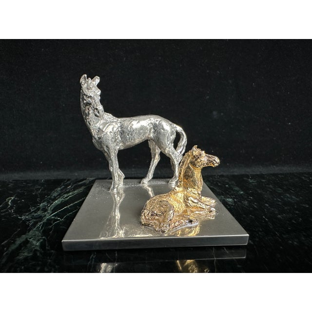 Two-tone metal figurine of a standing mare in silver-tone finish and a resting foal in gold-tone finish, mounted together...