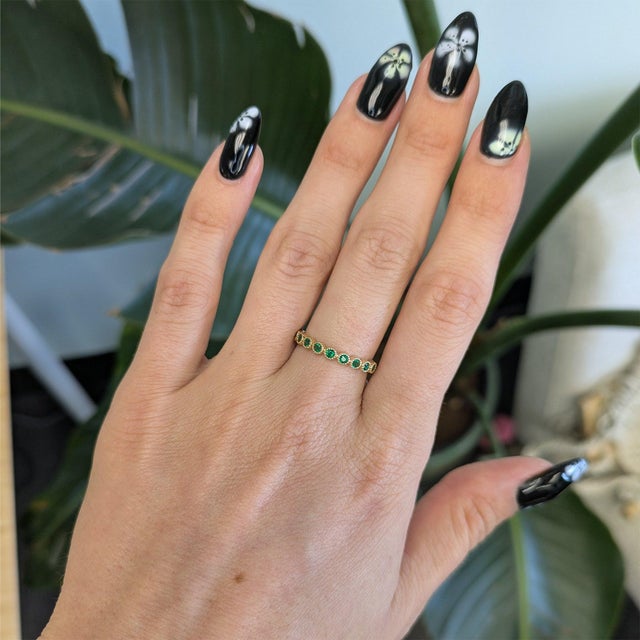 Ten round Zambian emeralds glow in a rich forest green across this solid 14K yellow gold band, with no center stone to...