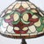 A vintage table lamp featuring a handcrafted leaded stained glass shade, characteristic of mid-20th century design. The...