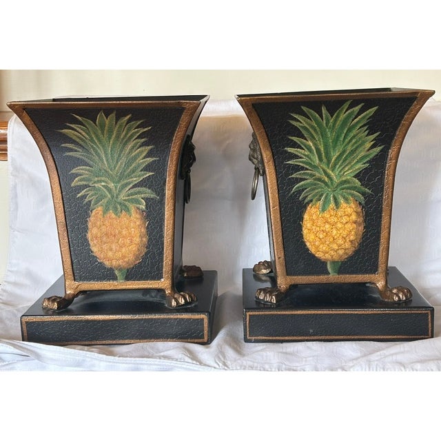 A pair of vintage tole planters with hand-painted pineapple motif on the front and back panels. Scrolled lion head handles...