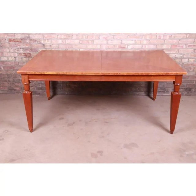 A beautiful Neoclassical style extension dining table By Baker Furniture USA, Circa 1990s Book-matched inlaid cherry wood,...