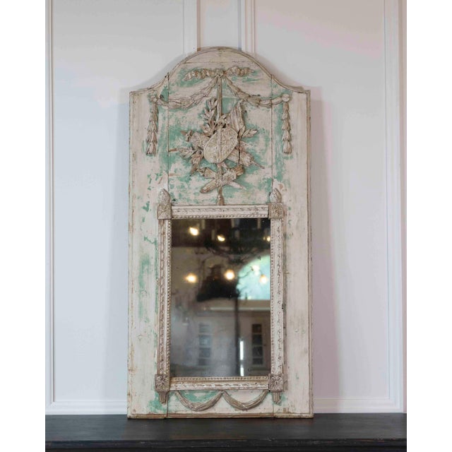 Made in France in the eighteenth century, this small Louis XVI trumeau mirror is carved in wood and decorated with warrior...