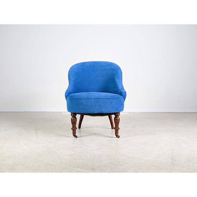 We are offering a beautiful Victorian armchair upholstered in dark blue velvet for sale. The armchair has small casters on...