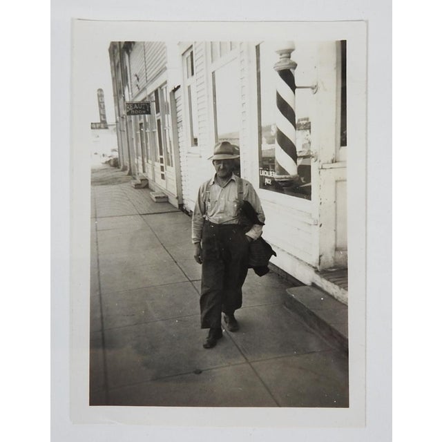 1950's vernacular snapshot photograph of cityscape with working man walking by a barber shop and barber pole. Unframed.