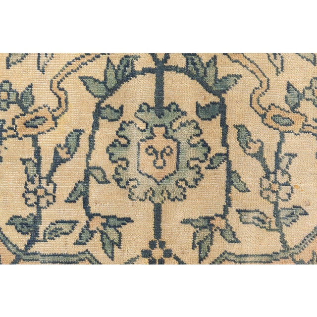 An Indian rug having a camel field with a delicately drawn allover pattern of flowering bushes and floral vinery within an...