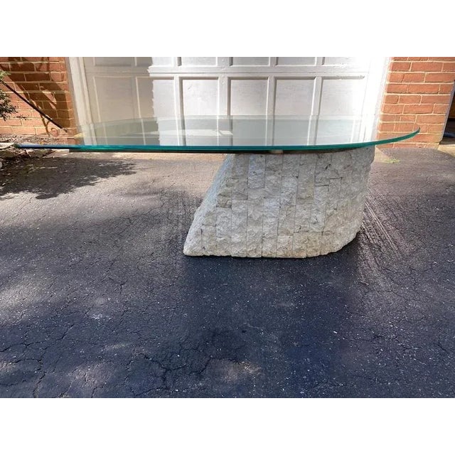 Gorgeous Postmodern 1980s design, freeform tessellated stone coffee table with textured stone base. The glass piece is...