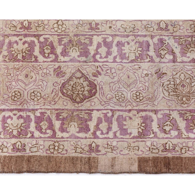 A handmade wool antique Persian Kirman rug dating back to 1920. The main field features a grid of angular flowers,...