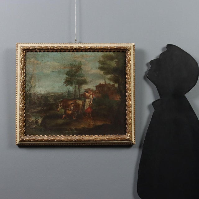 Oil on canvas. Venetian School, 18th century. In a countryside landscape with rolling hills, a woman milks her cow by the...