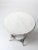 An antique wicker accent table with a round painted wood top, woven wicker base and lower stretcher shelf. The timeworn...