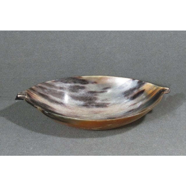 A vintage handcrafted bowl made from natural polished multicolor buffalo horn. The piece has an elegant elongated form...