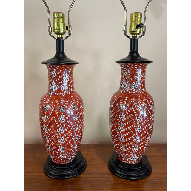 Sweet pair of vintage ginger jar style lamps. Hand painted white cherry blossoms bloom over a rich, persimmon glazed body...