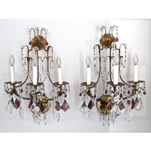 Pair of elegant 1940s gilt metal three-light wall sconces with clear and lavender crystals and beads. Each sconce uses 3...