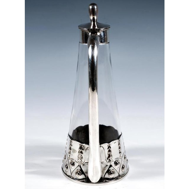 Art Nouveau glass carafe with exquisite silver mount: Glass carafe made of conical clear glass on a round base, with a...